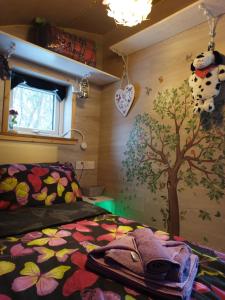 a bedroom with a bed with a tree on the wall at Butterfly PODika in Lerwick