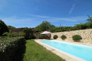 a swimming pool in a yard next to a stone wall at La métairie in Isle