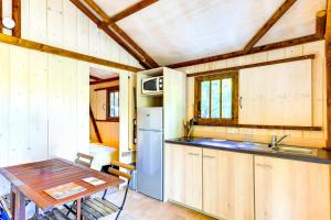 a kitchen with a table and a refrigerator at Cabanes Lodges Le Servière in Balazuc