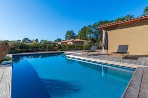 a swimming pool with two chairs next to a house at Villa U Capu - Piscine Privée in Lecci
