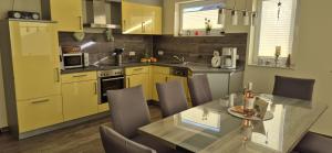 a kitchen with yellow cabinets and a table with chairs at Ferienhaus Seeschwalbe in Fehmarn
