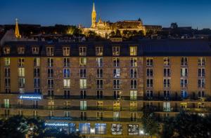 a building in front of a city at night at Park Plaza Budapest in Budapest