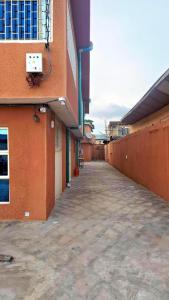 an empty walkway next to a orange building at Rennyshouse 3 Bedroom Apartments in Alimosho