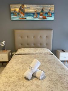 a towel on a bed with a painting of boats at Casa Las Flores Ica in Ica