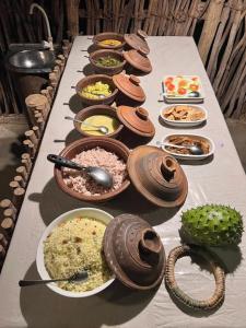 a long table filled with bowls and plates of food at Brooklyne Jungle Nest in Udawalawe