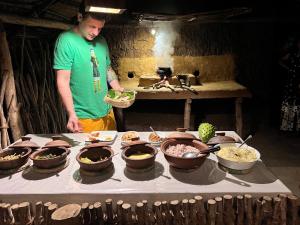 a man standing in front of a table with bowls of food at Brooklyne Jungle Nest in Udawalawe
