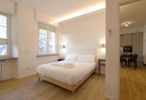 a white bedroom with a large bed and a table at LA FORESTERIA Case a Varese in Varese