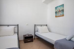a room with two beds and a night stand at Christine Beachside Villa Pefkos in Pefki