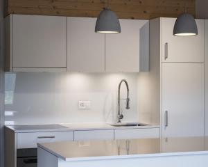 a white kitchen with white cabinets and a sink at Hotel Mulin by Amanthos in Breil/Brigels +86 photos