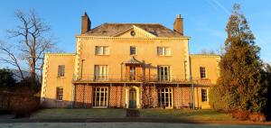 a large yellow house with a balcony in front of it at Little Plas in Crickhowell