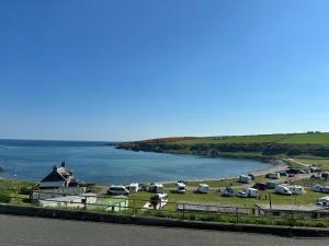 a group of cars parked in a field next to a body of water at Luxury Coastal Cottage in Portsoy