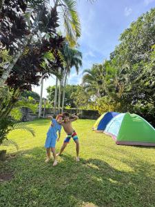 two people standing in the grass near a tent at Casa de Campo Vive in Ensanche Savica de Mendoza