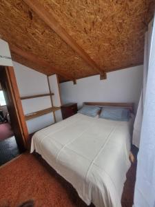 a bedroom with a white bed with a wooden ceiling at Cabaña Cielo Patagonico in Futaleufú