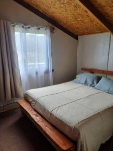 a bed in a bedroom with a large window at Cabaña Cielo Patagonico in Futaleufú +6 photos