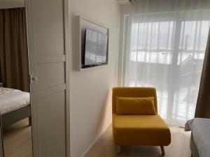 a yellow chair sitting in a room with a window at Rooms Brussels Airport- 'The Good Place' in Zaventem +9 photos