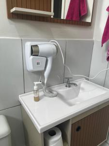 a hair dryer sitting on a sink in a bathroom at Apto 2 quartos, Wi-Fi rápido, Self check in in Uberlândia +18 photos