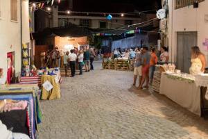 a group of people standing in a market with tables at Casa da avo Rita in Pêro Viseu
