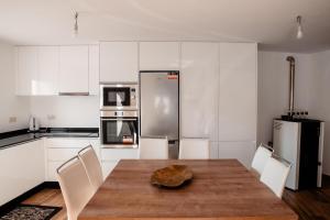 a kitchen with a wooden table and white cabinets at Casa da avo Rita in Pêro Viseu