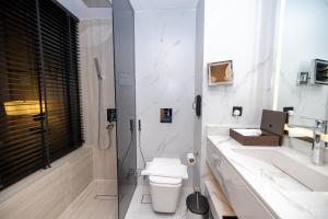 a white bathroom with a toilet and a shower at 7Crown Tahliah Hotel in Riyadh +31 photos