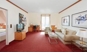 a living room with a couch and a tv at Living Hotel Großer Kurfürst in Berlin