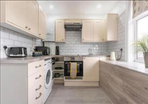 a kitchen with white cabinets and a washer and dryer at Walsgrave Road 3BR Multi-Floor Apartment Unit - Free Parking & WiFi in Wyken