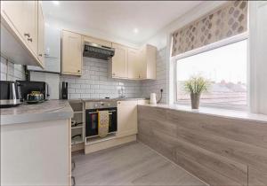 a kitchen with white cabinets and a large window at Walsgrave Road 3BR Multi-Floor Apartment Unit - Free Parking & WiFi in Wyken +2 photos