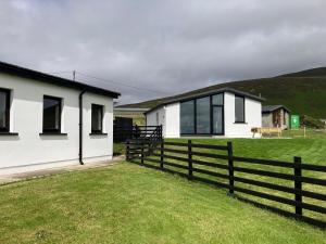 a white house with a fence next to a field at Silver Strand Chalets - Chalet 2 in Malin Beg