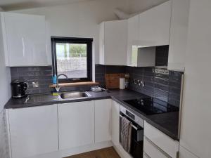 a kitchen with white cabinets and a sink and a window at Silver Strand Chalets - Chalet 2 in Malin Beg