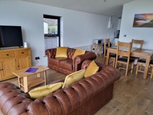 a living room with two brown leather couches and a table at Silver Strand Chalets - Chalet 2 in Malin Beg