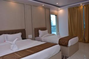 a hotel room with two beds and a window at Hotel Devi Palace in Rājgīr