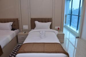two beds in a room with two windows at Hotel Devi Palace in Rājgīr +9 photos