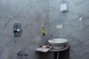 a bathroom with a sink and a marble wall at Hotel Devi Palace in Rājgīr