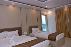 a hotel room with two beds and a window at Hotel Devi Palace in Rājgīr