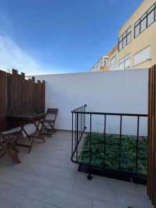 a balcony with a table and chairs and a white wall at Casa Do Campo in Peniche