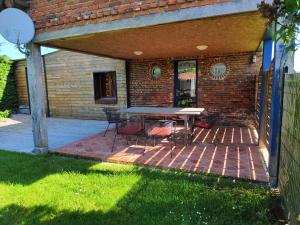 a patio with a table and chairs on a brick wall at Le gîte des hallais in Bouelles