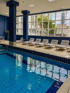 ein großes Schwimmbecken mit Liegestühlen und ein Gebäude in der Unterkunft Hotel Blumenau by Pires - Balneário Camboriú in Balneário Camboriú