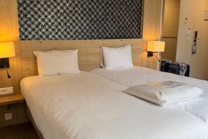 two beds in a hotel room with white sheets and pillows at Kyriad Vannes Centre Ville in Vannes +51 photos