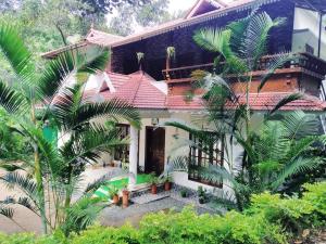 a house with a red roof and some palm trees at Spring Dale Homestay in Thekkady