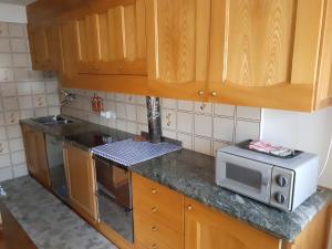 a kitchen with wooden cabinets and a microwave at Casa Milpa in Sappada +4 photos