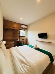 a bedroom with a bed and a tv on the wall at Saptama Living in Citaringgul 1