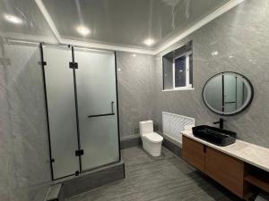 a bathroom with a shower and a toilet and a mirror at Hotel VANGOGH in Kyzylorda