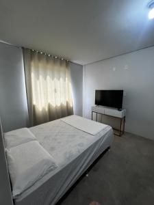 a bedroom with a bed and a flat screen tv at Shiva Hostel in Rio das Ostras