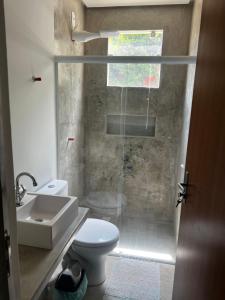 a bathroom with a shower and a toilet and a sink at Shiva Hostel in Rio das Ostras