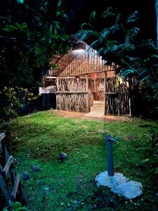 a wooden building with a gate in the grass at Brooklyne Jungle Nest in Udawalawe