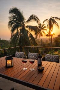 two glasses of wine on a wooden table with the sunset at Villa Nomada Exclusive Modern Seaview Spa and Wellness Villa with Daily Housekeeping 5 Bedrooms Sauna Ice Bath and 20 Meter Private Saltwater Pool in Ban Bang Po