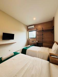 a hotel room with two beds and a flat screen tv at Saptama Living in Citaringgul 1