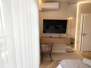 a living room with a television and a chair in a room at Downtown Shkodra Apartment in Shkodër