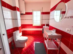 a red and white bathroom with a toilet and a sink at Downtown Shkodra Apartment in Shkodër +19 photos