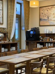 ein Esszimmer mit Tischen und Stühlen und einem Fernseher in der Unterkunft Memel Hotel in Klaipėda