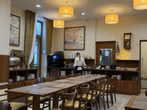 Eine Frau steht in einem Restaurant mit einem Tisch und Stühlen. in der Unterkunft Memel Hotel in Klaipėda
